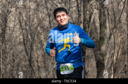 ALMATY, Kasachstan - 16. März 2019: Porträt einer stattlichen Reifen unbekannter Mann, der durch die Wälder im Frühjahr beim Marathon in der Stadt läuft Stockfoto