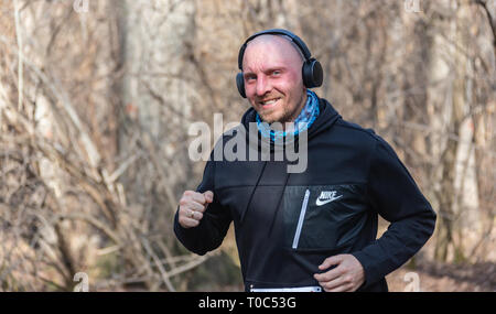 ALMATY, Kasachstan - 16. März 2019: Porträt einer stattlichen Reifen unbekannter Mann, der durch die Wälder im Frühjahr beim Marathon in der Stadt läuft Stockfoto