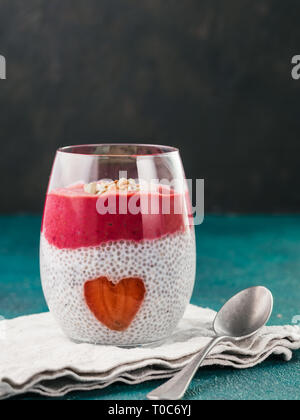 Idee für gesundes Frühstück am Valentinstag: Chia Pudding mit roten Beeren Püree, gehackte Mandeln auf und Erdbeere in der Form des Herzens. Kopieren Sie Platz für Text Stockfoto