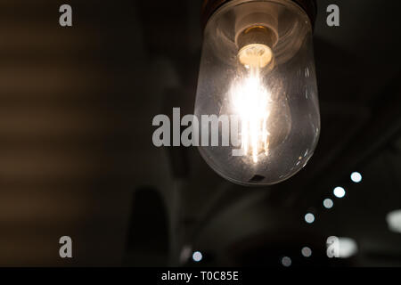 Glühende vintage Glühbirne aus der engen Perspektive in der Dunkelheit Stockfoto