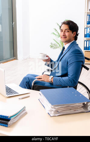 Männliche Angestellte im Rollstuhl im Büro arbeiten Stockfoto