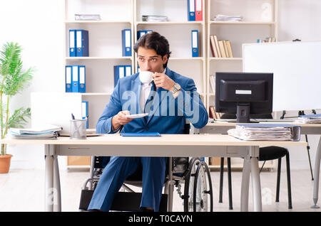 Männliche Angestellte im Rollstuhl im Büro arbeiten Stockfoto