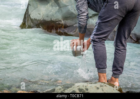 Srinagar, Jammu und Kaschmir, Indien: Datum - 20. Juli 2018: eine Person waschen Geschirr in einem Fluss mit schnell fließendem Wasser Stockfoto