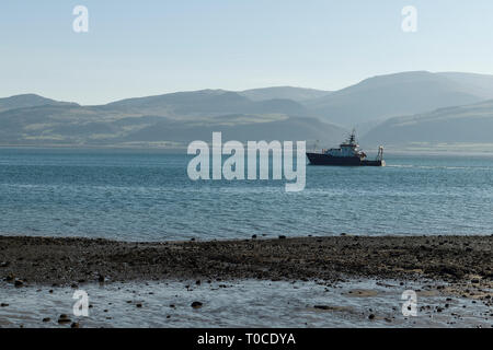 Der Bangor University Forschungsschiff Prinz Madog reist Vergangenheit Beaumaris entlang der Menaistraße mit dem Snowdonia Gebirge im Hintergrund. Stockfoto