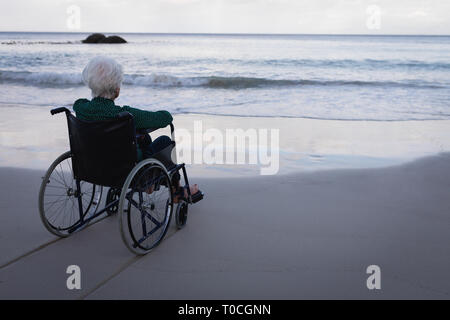 Deaktiviert die Active Senior Frau am Meer sitzend auf Rollstuhl am Strand Stockfoto