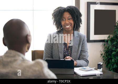 Schwarze weibliche Geschäftsfrau in einem Büro mit einem Client geben rechtliche Beratung über Steuern oder Darlehen. Die Frau könnte ein Rechtsanwalt oder ein cpa-Konto Stockfoto