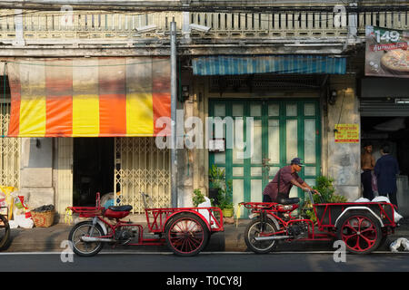 Eine Straße in der Altstadt von Bangkok, Thailand, mit Traditionellen Chinesischen Geschäftshäusern und waren auf ein Motorrad mit Last Bereich geladen werden Stockfoto