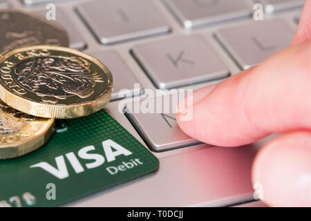 Online Banking, Online Shopping Konzept. Visa Debit Card & Münzen auf einem Laptop Tastatur. Vereinigtes Königreich Stockfoto