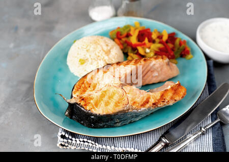 Gegrilltes Lachssteak mit gedünsteten Paprika und Reis auf grauem Hintergrund Stockfoto