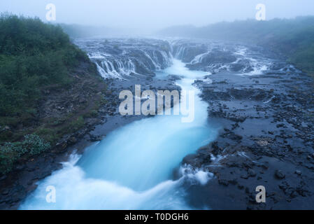 Landschaft mit einem beeindruckenden Wasserfall Bruarfoss. Das Wasser ist türkis Farbe und schönen Wasserfällen. Touristische Attraktion in Island. Morgennebel Stockfoto