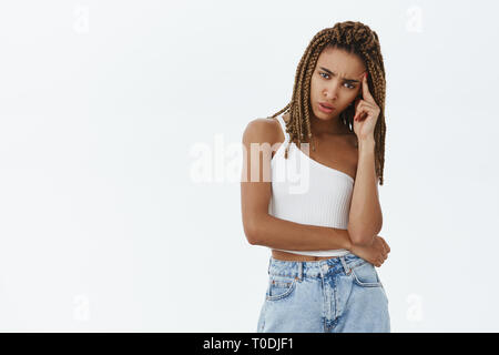 Intensive verärgert, Frau, die versucht, zu verstehen, was Menschen wollen finger Festhalten am Tempel schiefen Kopf stand ratlos und gestört, die versuchen, sie hängen von Sprechen Stockfoto