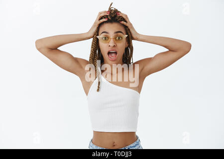 Taille - geschossen von eleganten dunklen - Party girl in modischen Sonnenbrillen und top Kreischen fehlt Zeit zum dress-up, Hände auf den Kopf mit dreads gehäutet Stockfoto