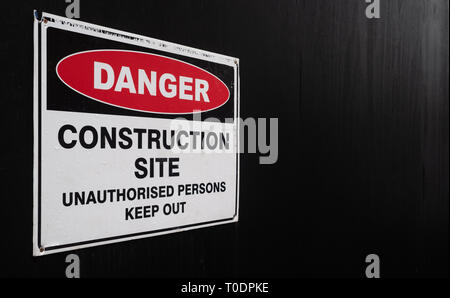 Baustelle Warnschild, gegen eine schwarz lackierte Zaun Stockfoto
