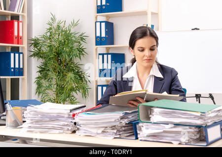Weibliche Mitarbeiter mit zu viel Arbeit im Büro Stockfoto