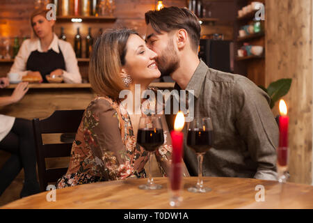 Romantisches Paar dating in einem Vintage Restaurant. Schöner Mann küssen sanft seine Freundin Wange Stockfoto