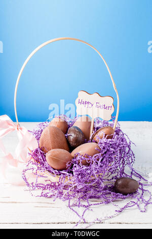 Bild von Huhn, Schokolade, Eier, lila Dekorpapier in Korb, wünschen Frohe Ostern Stockfoto