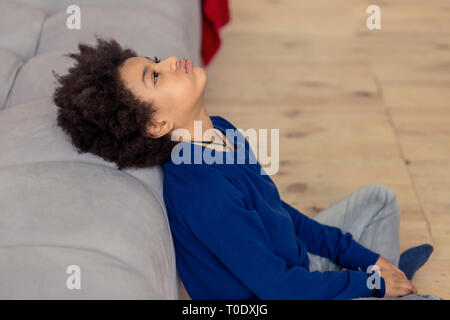 Kind sitzt auf dem Boden in der Nähe von Sofa umgekippt Stockfoto