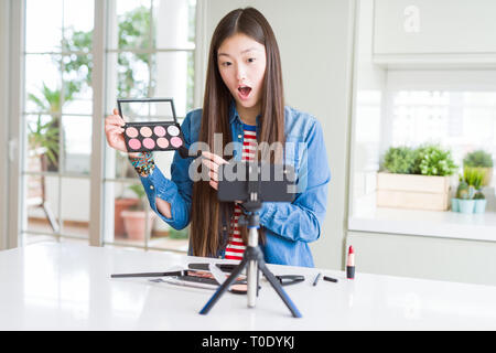 Schöne asiatische Einflussnehmer Frau Aufnahme Make-up Tutorial über Smartphone-kamera im Schlag mit einer Überraschung konfrontiert, ängstlich und aufgeregt mit Angst Angst Stockfoto