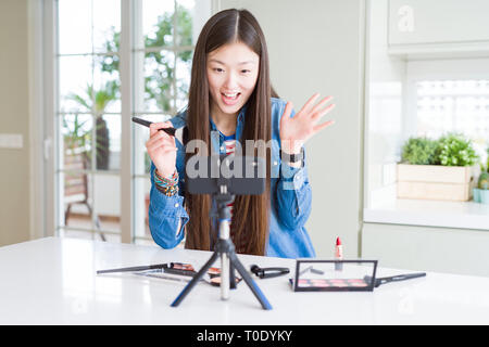 Schöne asiatische Einflussnehmer Frau Aufnahme Make-up Tutorial über Smartphone-kamera sehr glücklich und aufgeregt, Sieger Ausdruck feiern Sieg scre Stockfoto