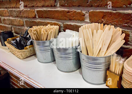 Nahaufnahme der verschiedenen verfügbaren Holzstäbchen, Kochlöffel, Zahn Sticks, Tasse deckt, Boxen, Servietten und Zucker Taschen auf Holz- Zähler Stockfoto