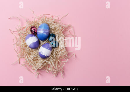 Festliche Ostern Kopie Raum mit bunten Eier im Nest auf rosa Hintergrund. Konzept der Ostereier. Rechten Rand kopieren Raum, Flach, vertikale Bild Stockfoto