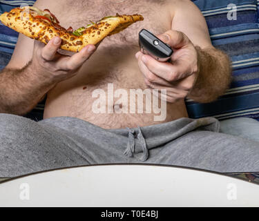 Fat man essen Pizza und über Fernbedienung, ungesunde Lebensweise Konzept Stockfoto