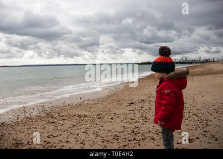 Junge zwei im roten Mantel spielen am Strand im Frühling mit Bommel hat im Alter von Stockfoto