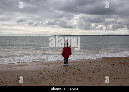 Junge zwei im roten Mantel spielen am Strand im Frühling mit Bommel hat im Alter von Stockfoto