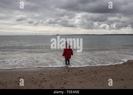 Junge zwei im roten Mantel spielen am Strand im Frühling mit Bommel hat im Alter von Stockfoto