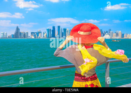 Katar Travel Concept. Elegante kaukasische Frau Untersuchungsarbeit der Blick auf Doha West Bay. Blond Tourist in Doha in der Innenstadt von Osten Mound-Skyline Sicht Stockfoto