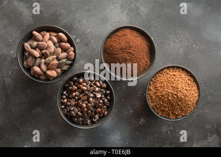Konzept der Kakao- und Kaffeebohnen in Schalen auf schwarzem Hintergrund. Stockfoto