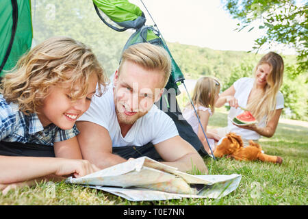 Vater und Sohn im Zelt betrachten eine Karte auf Campingurlaub im Sommer Stockfoto