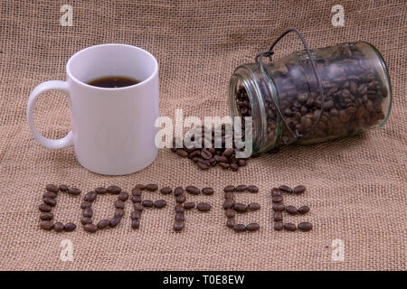 Kaffee Bohnen, Kaffee, Kaffeetasse, und ein Glas mit Bohnen, verschüttet Stockfoto