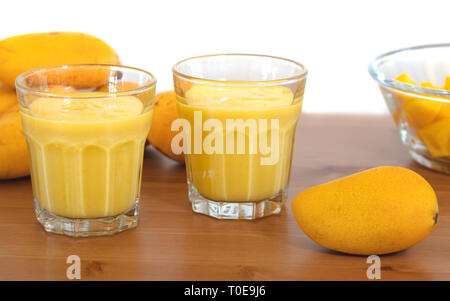 Mango Milchshake in Glas mit gelben baby Mangos mit weißem Hintergrund gemacht Stockfoto