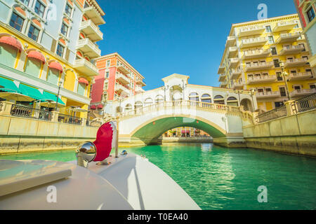 Venezianische Brücke auf die Kanäle der malerischen Qanat Quartier Symbol von Doha, Katar aus einem touristischen Boot mit Flagge von Qatar. Venedig im Pearl, Persisch Stockfoto