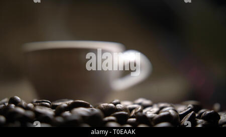 Tasse mit heißem Kaffee steht auf Kaffeebohnen Stockfoto