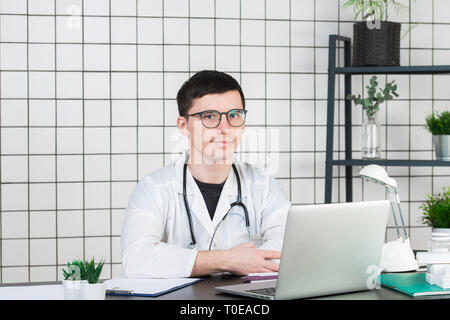 Medizin, Beruf, Technik und Mensch Konzept - Lächeln männlicher Arzt mit Laptop im medizinischen Büro Stockfoto