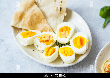 Gekochte Eier in Hälften, gewürzt mit Salz und Pfeffer mit pita Brot auf den Teller geschnitten, gesunde Vorspeisen Mahlzeit Stockfoto