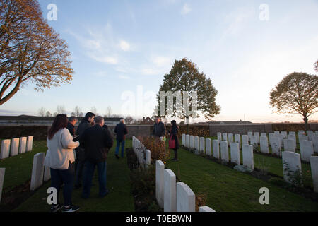 Ein Reiseleiter zeigt Touristen die Gräber der gefallenen Soldaten des Ersten Weltkrieges, als sie inmitten der Grabsteine auf einem Friedhof in Frankreich gehen. Stockfoto