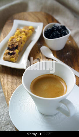 Gesundes Frühstück Tasse Kaffee und süßes Cookies mit Rosinen Corn Flakes und Brombeeren. Cookies auf Platte Tischdecke. Brombeeren auf weiße Schüssel Stockfoto