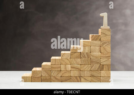 Konzept des Wachstums. Grafik mit Holzstufen auf grauem Hintergrund mit Nummer eins an der Spitze. Stockfoto