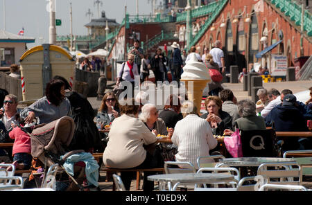 Urlauber genießen Sie Erfrischungen vor einem Cafe an der Strandpromenade von Brighton, Sussex, England sitzen. Stockfoto