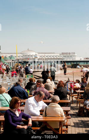 Urlauber genießen Sie Erfrischungen vor einem Cafe an der Strandpromenade von Brighton, Sussex, England sitzen. Stockfoto