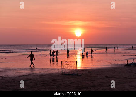 BALI - Indonesien/06.03.208: Menschen zu Fuß und genießen den Sonnenuntergang am Strand von Kuta bei Ebbe, Insel Bali, Indonesien Stockfoto