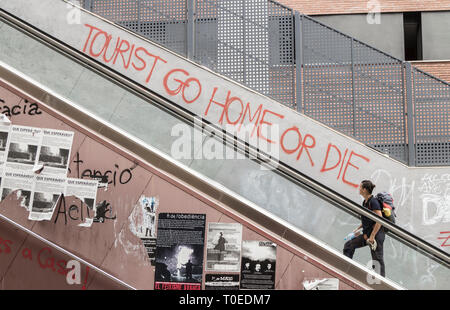 "Touristen gehen nach Hause oder sterben" an der Wand in der Nähe der Rolltreppe in Barcelona, Spanien. Konzept des Coronavirus...