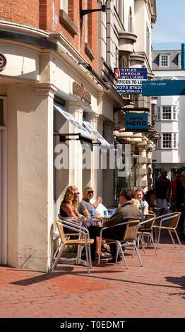 Menschen außerhalb Caffe Nero in der Küstenstadt Brighton, Sussex, England sitzen. Stockfoto