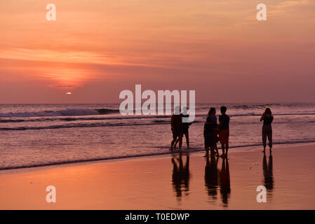 BALI - Indonesien/06.03.208: Menschen zu Fuß und genießen den Sonnenuntergang am Strand von Kuta bei Ebbe, Insel Bali, Indonesien Stockfoto