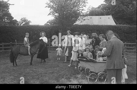 1948, Mütter mit ihren Kindern an einem Garten Fete, mit ein wenig Junge sitzt auf einem Pony, England, UK. Stockfoto