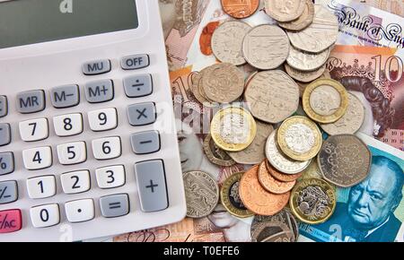 Britische Banknoten und Münzen neben Taschenrechner Stockfoto