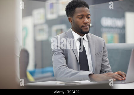 Portrait von Stattlichen afrikanischen Geschäftsmann mit Laptop, während im Büro arbeiten, kopieren Raum Stockfoto